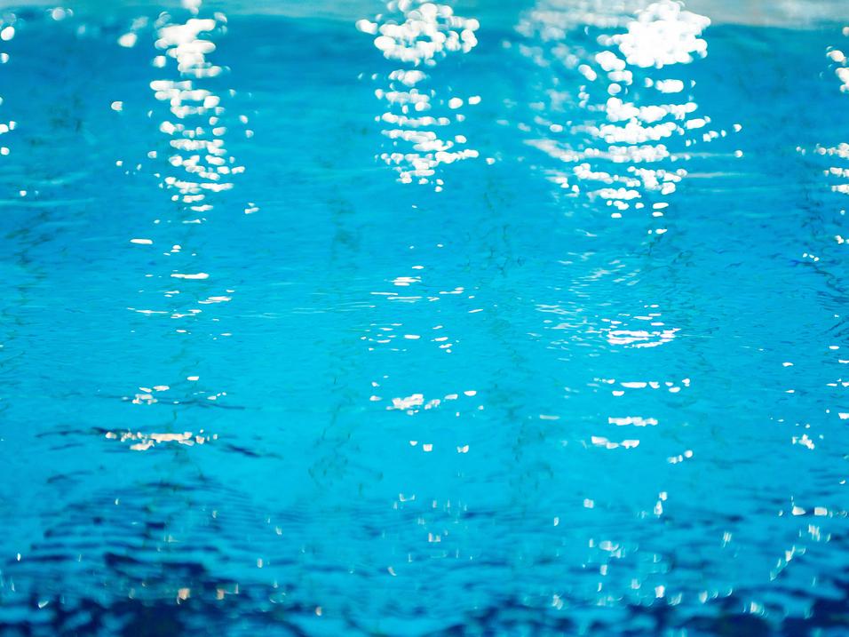 Wasseroberfläche mit Lichtreflexionen in verschiedenen Blau- und Türkistönen. Sanfte Wellenbewegungen sichtbar.